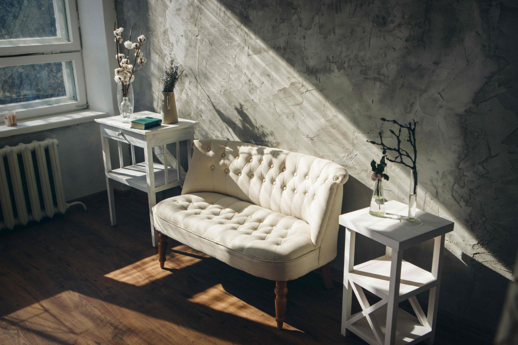 Sofa mit Beistelltischen vor einem Fenster.