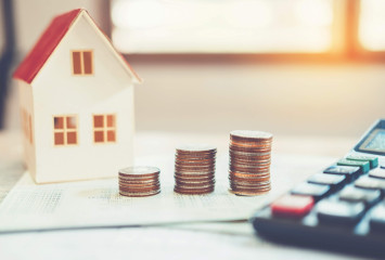 Modellhaus mit Münzen und Taschenrechner